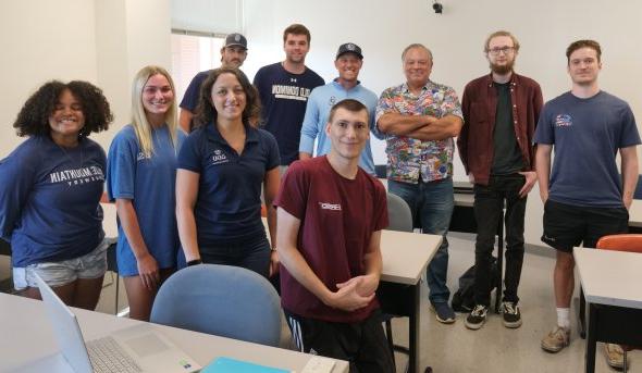 A group of students stand in a classroom.