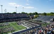 Thousands of people sit before a stage in a stadium.